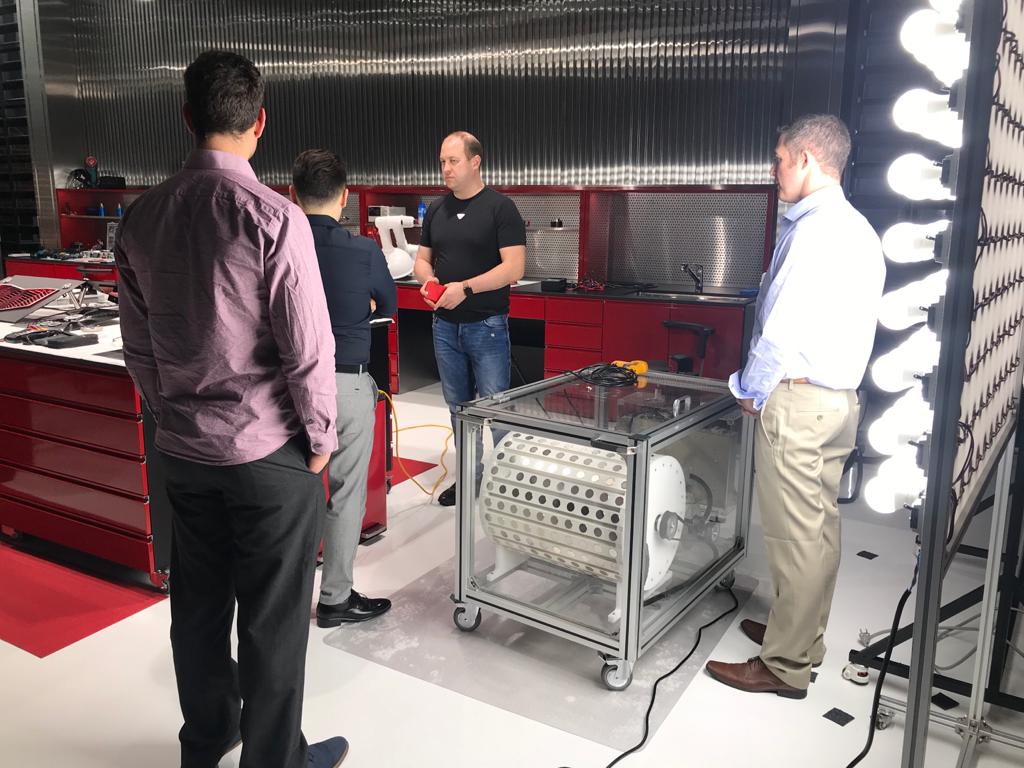 The MG10 magnetic motor-generator on its rolling cart — the team gathered around the prototype in the lab