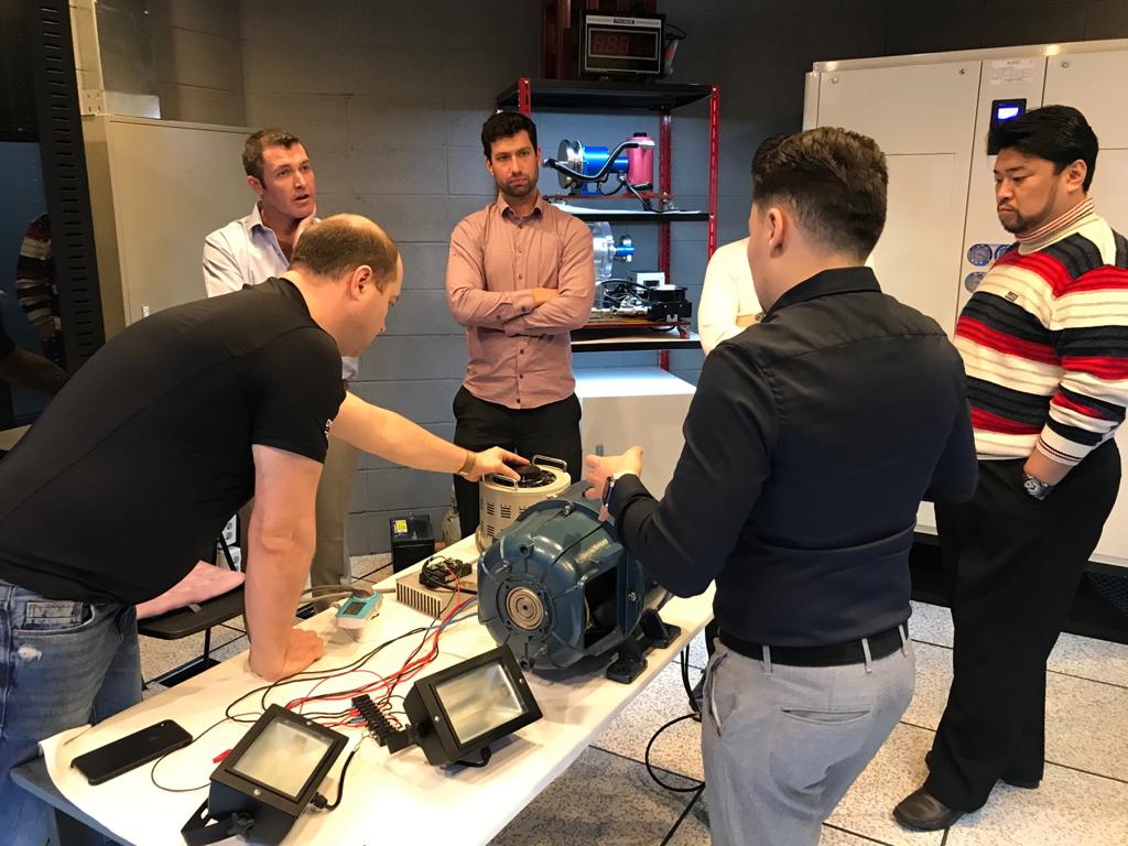 Andrii demonstrates the motor-generator components at the workbench — instruments and measurement equipment visible