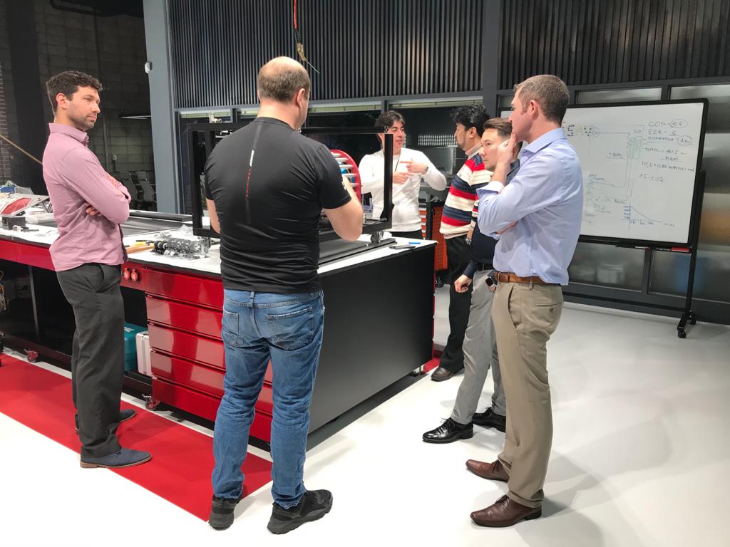 Team discussion at the whiteboard — reviewing COP calculations and system diagrams