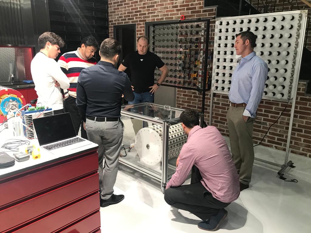 The full team gathered around the motor-generator prototype during evaluation