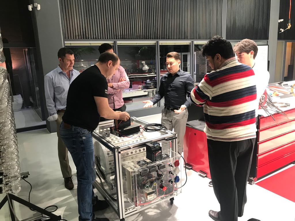 Andrii presents the MG10 system internals — clear acrylic enclosure showing power electronics and motor assembly