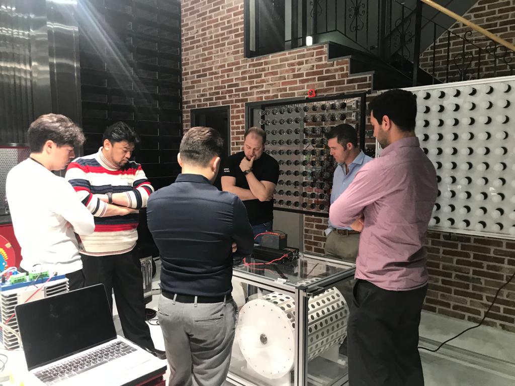 The full team deep in discussion around the MG10 prototype — a pivotal moment in the acquisition evaluation